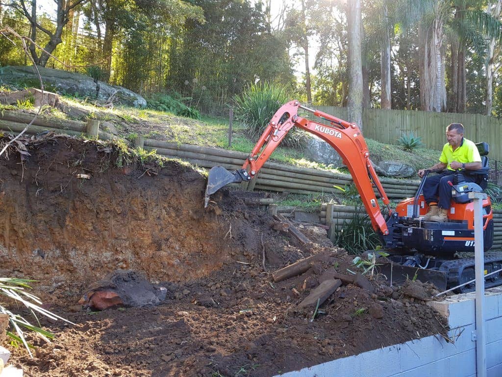 mini excavator digging retaining wall
